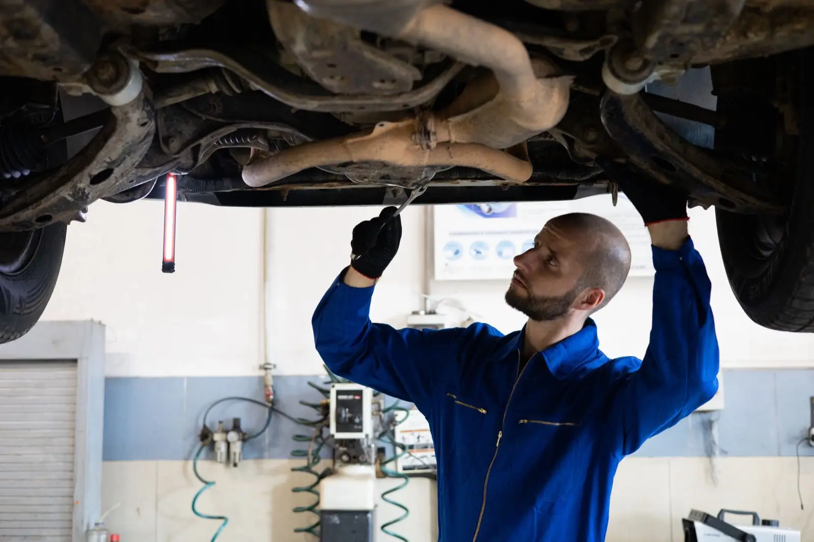 Mechaniker prüft den Unterboden eines Autos auf der Hebebühne