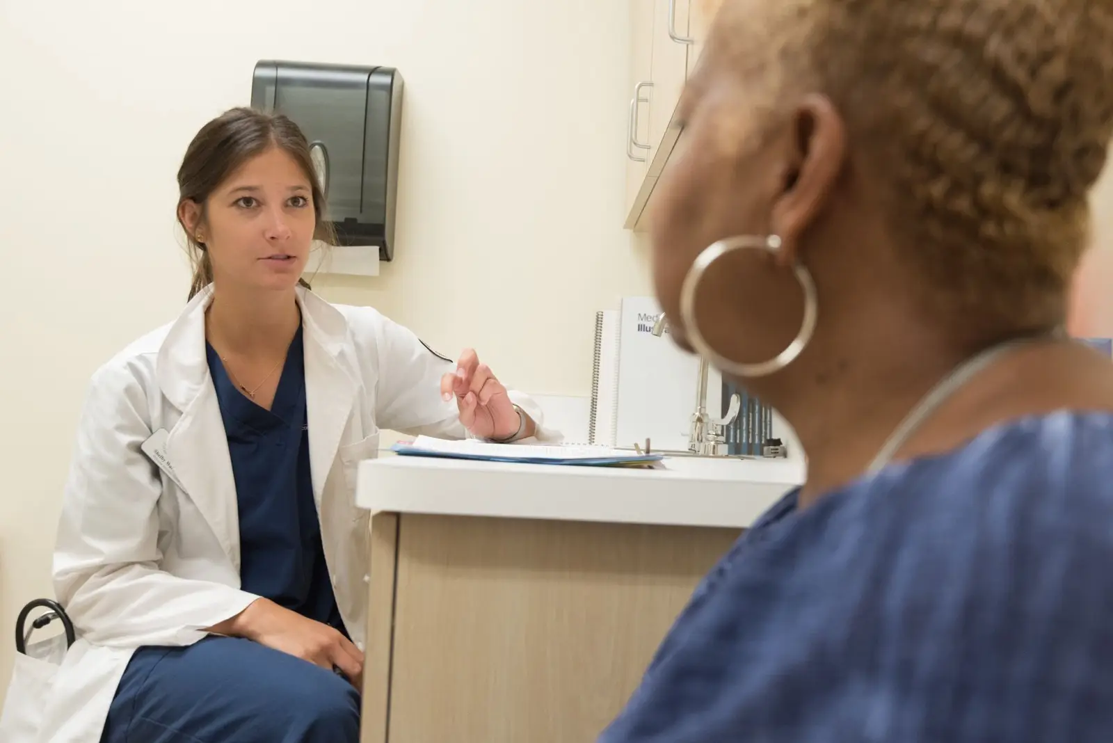 Ärztin im Gespräch mit einer Patientin am Schreibtisch der Ordination